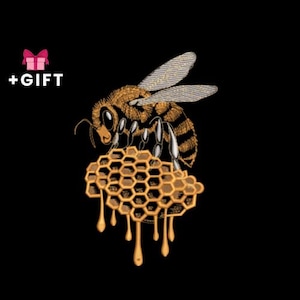 May include: An embroidered design of a honeybee perched on a honeycomb, with honey dripping down. The bee is detailed with brown and black stripes, and the honeycomb is a golden yellow. The words "+ GIFT" are above a pink gift box.