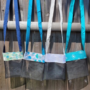 May include: Four mesh bags with different fabric straps and colorful fabric panels. The bags are hanging on a wooden fence.