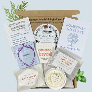 Puede incluir: Una caja de cartón marrón llena de artículos de cuidado personal. La caja contiene bombas de baño, bolsitas de té, una tarjeta pequeña que dice "You are loved", una tarjeta pequeña que dice "Sometimes there are no words", y una tarjeta pequeña que dice "Difficult day reminders".