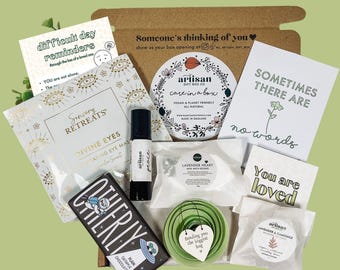 May include: A brown cardboard box filled with self-care items, including a bath bomb, a candle, a chocolate bar, and a card that says "Sometimes there are no words".
