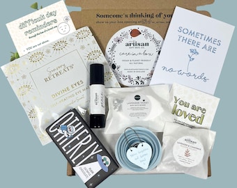 May include: A gift box filled with self-care items. Includes a chocolate bar, eye mask, bath bombs, essential oil roller, and cards with encouraging messages. The box is decorated with the words "Someone's thinking of you."