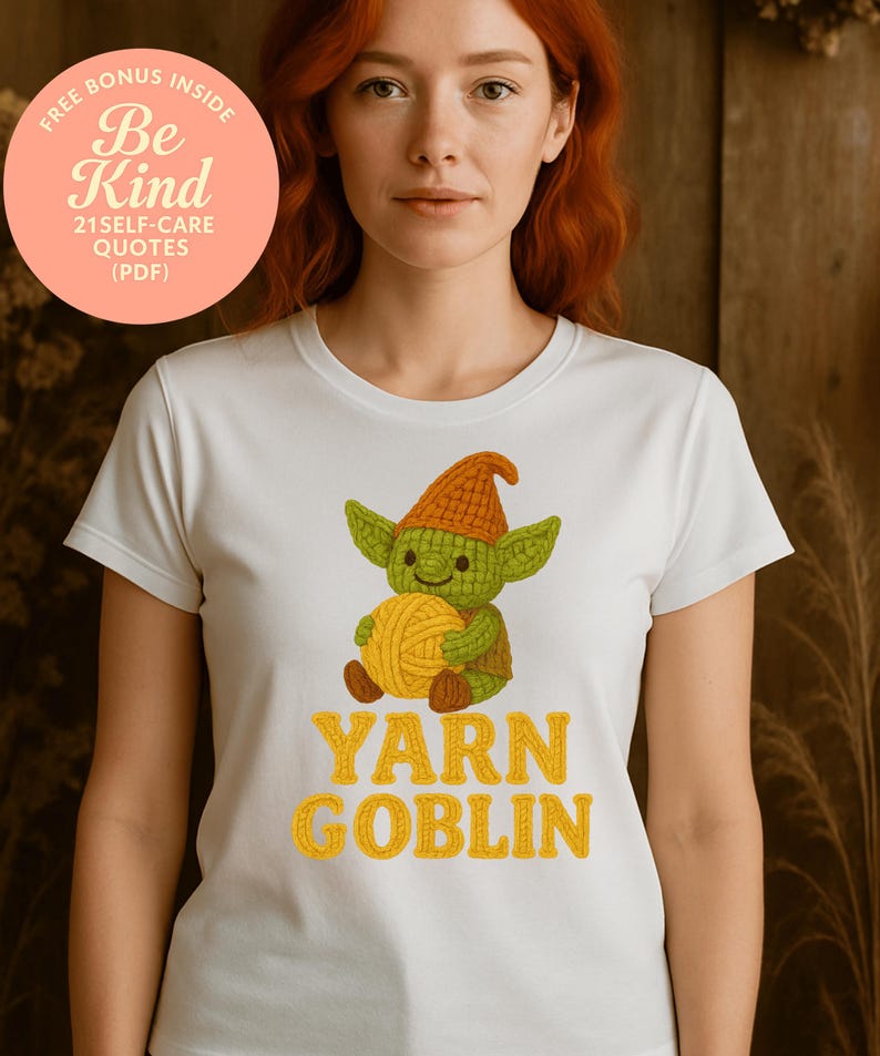 May include: White t-shirt featuring a cartoon goblin holding a ball of yarn. The goblin is green with an orange hat and brown shoes. The text "YARN GOBLIN" is in yellow. A pink circle with text is in the upper left corner.