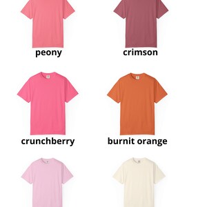 May include: A collection of six short-sleeved t-shirts in various colors: peony, crimson, crunchberry, burnt orange, blossom, and ivory. Each shirt has a crew neck and is displayed on a white background.