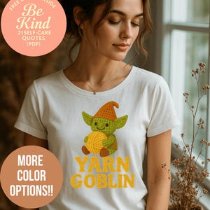 May include: White t-shirt featuring a cartoon goblin holding yarn, with the text "YARN GOBLIN" in yellow. The shirt also has a circular graphic with the text "Be Kind" and "21 SELF-CARE QUOTES (PDF)". A second graphic says "MORE COLOR OPTIONS!!".