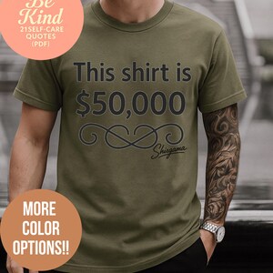 May include: Olive green t-shirt with the text "This shirt is $50,000" in black. The shirt also features an infinity symbol design and the brand name "Shisgama". Additional text includes "More Color Options!!" and "Free Bonus Inside Be Kind 21 Self-Care Quotes (PDF)".