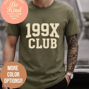 May include: An olive green t-shirt with the text "199X CLUB" in a cream-coloured, collegiate-style font. The shirt also features two circular graphics with text: "FREE BONUS INSIDE Be Kind 21 SELF-CARE QUOTES (PDF)" and "MORE COLOUR OPTIONS!!"
