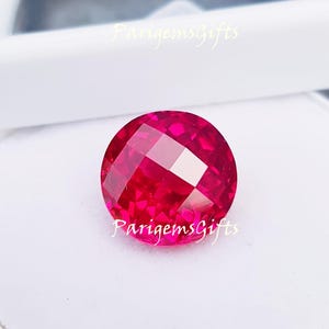 Könnte beinhalten: Ein facettierter, runder, leuchtend rosa Edelstein. Der Edelstein hat ein komplexes Muster aus reflektierenden Oberflächen, das das Licht einfängt. Der Text "ParigemsGifts" ist auf dem Bild sichtbar. Geeignet für die Schmuckherstellung.