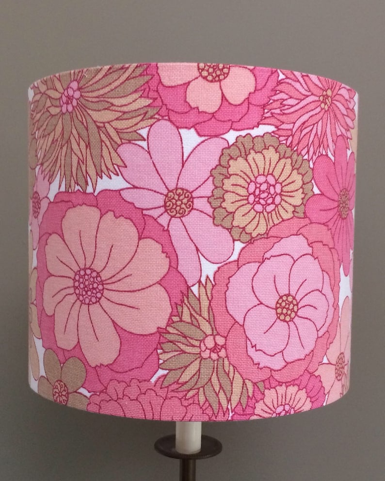 May include: A pink and brown floral lampshade with a white background. The lampshade has a large, bold floral pattern with pink and brown flowers.