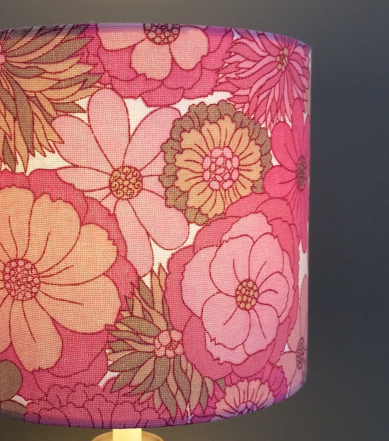 May include: A pink and brown floral lampshade with a retro design. The lampshade features a variety of flowers in different sizes and shapes.