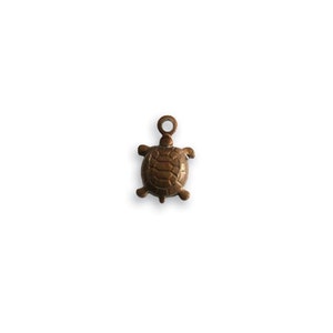 May include: A small, bronze-colored turtle charm with a detailed shell design. The charm has a loop at the top for attaching to a necklace or bracelet.