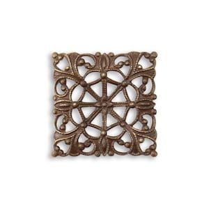 May include: A square, bronze-colored filigree embellishment with an ornate, openwork design. The decorative piece features a central starburst pattern surrounded by swirling floral and dot details. The metal has a slightly aged appearance.