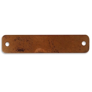 May include: A rectangular, brown metal tag with two holes. The tag has a rustic, aged look.