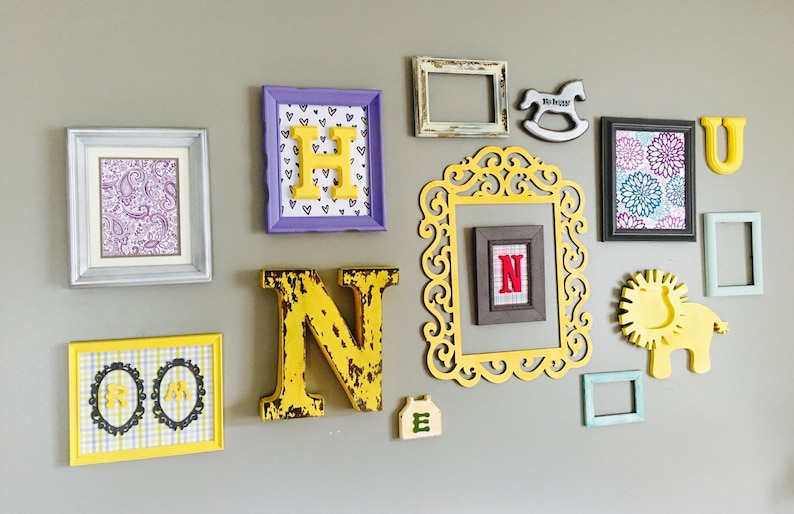 May include: A wall gallery featuring a variety of framed artwork, including a paisley pattern, a checkered pattern, and a floral design. The gallery also includes wooden letters spelling out the word "HUNTER" in yellow and a small wooden rocking horse.