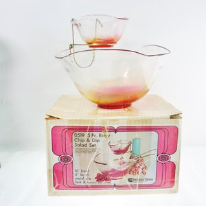 May include: A vintage 5-piece Ruby Chip & Dip Salad Set. The set includes a large bowl and a smaller bowl suspended above it, both with a ruby red base. The set is in its original box, which features the product name and a graphic illustration.