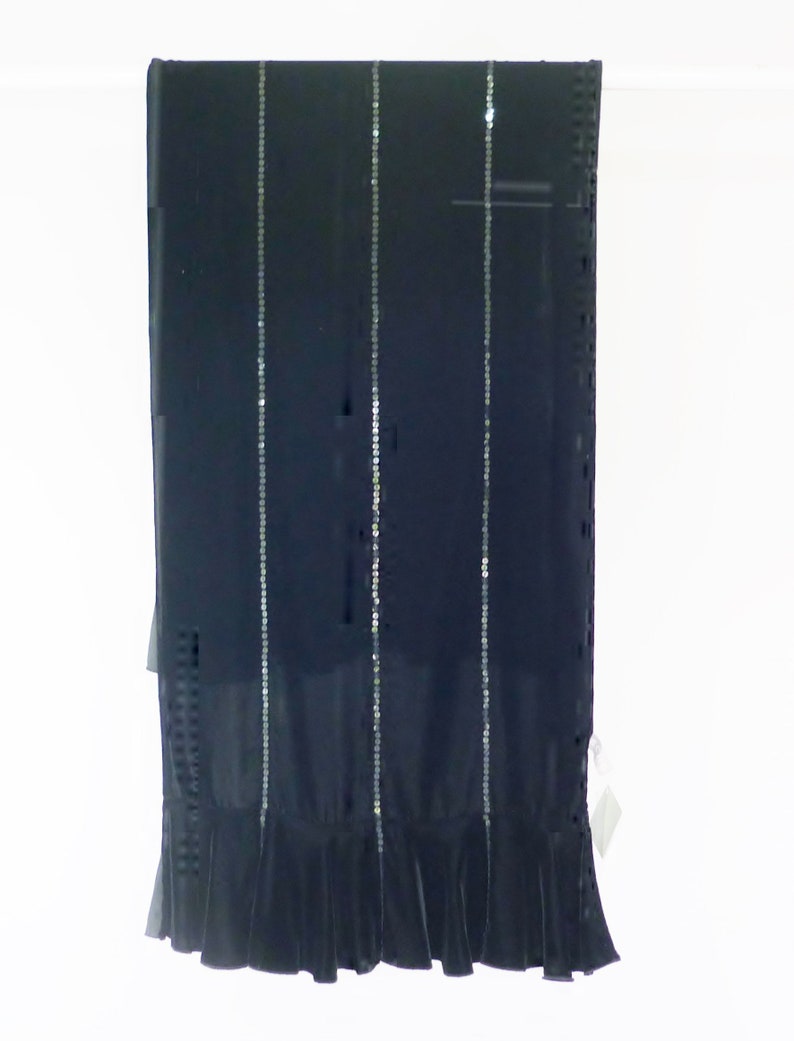 May include: A long, black scarf with vertical rows of silver sequins. The scarf has a ruffled hem at the bottom. The fabric appears to be a sheer material.