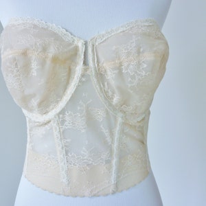 May include: A white lace strapless corset with a hook and eye closure in the front.