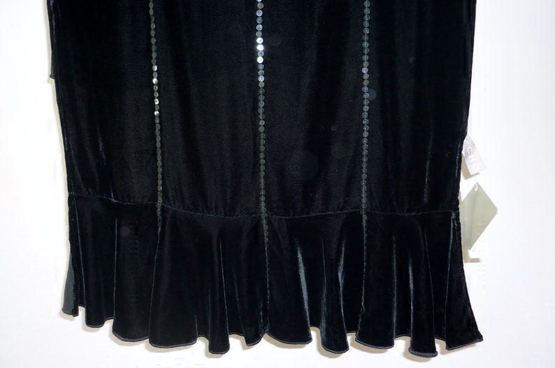 May include: Black velvet dress with vertical rows of sequins. The dress features a flared hemline. The fabric has a soft, luxurious appearance. The dress is suitable for formal occasions.