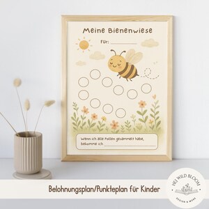 Pode incluir: Uma impressão emoldurada com tema de abelha. A impressão apresenta uma abelha de desenho animado, flores e o texto "Meine Bienenwiese" e "Belohnungsplan/Punkteplan für Kinder". A impressão está em uma moldura de madeira clara.