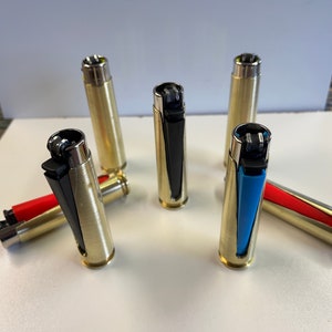 May include: Six gold-colored lighters with different colored inserts. The inserts are black, red, blue, and light blue.