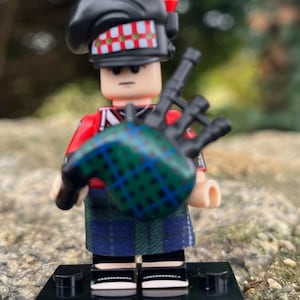 Minifigura escocesa Piper con falda escocesa tocando la gaita, con base y espada, incluye mini vitrina.