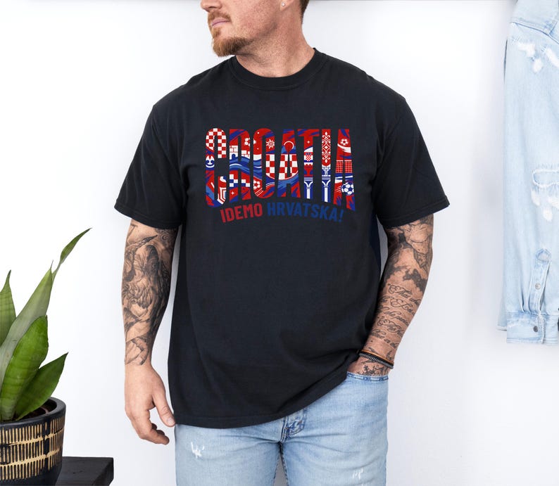 May include: Black t-shirt with a Croatian flag design. The word "CROATIA" is displayed in a stylized font, incorporating red, white, and blue elements. Below the word is the phrase "IDEMO HRVATSKA!"