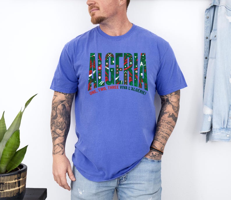 K&ouml;nnte beinhalten: Ein blaues T-Shirt mit dem Wort "ALGERIA" in einem gr&uuml;n-roten Muster. Darunter steht der Text "ONE, TWO, THREE VIVA L'ALG&Eacute;RIE!"