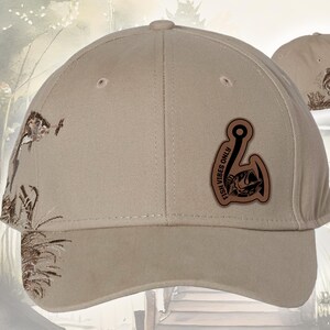 May include: Tan baseball cap with a brown leather patch featuring a fish hook and a bass. The cap has a curved brim and a fish graphic on the side. The text "FISH VIBES ONLY" is on the patch.