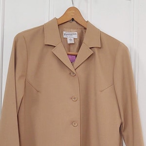 May include: A tan blazer with a collared neckline and button closure. The blazer has a label that reads "Pendelton".