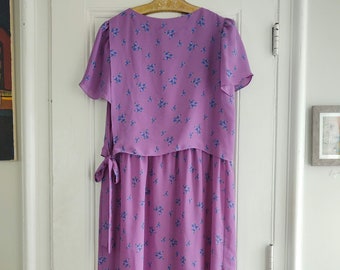 May include: A purple midi dress with a floral print. The dress has a V-neckline, short sleeves, and a tie at the waist.