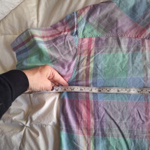 K&ouml;nnte beinhalten: Ein pastellfarbenes kariertes Button-Down-Hemd in Rosa-, Blau-, Gr&uuml;n- und Lilat&ouml;nen. Das Hemd wird mit einem Ma&szlig;band gemessen. Die Ma&szlig;e des Hemdes werden in Zentimetern gemessen.
