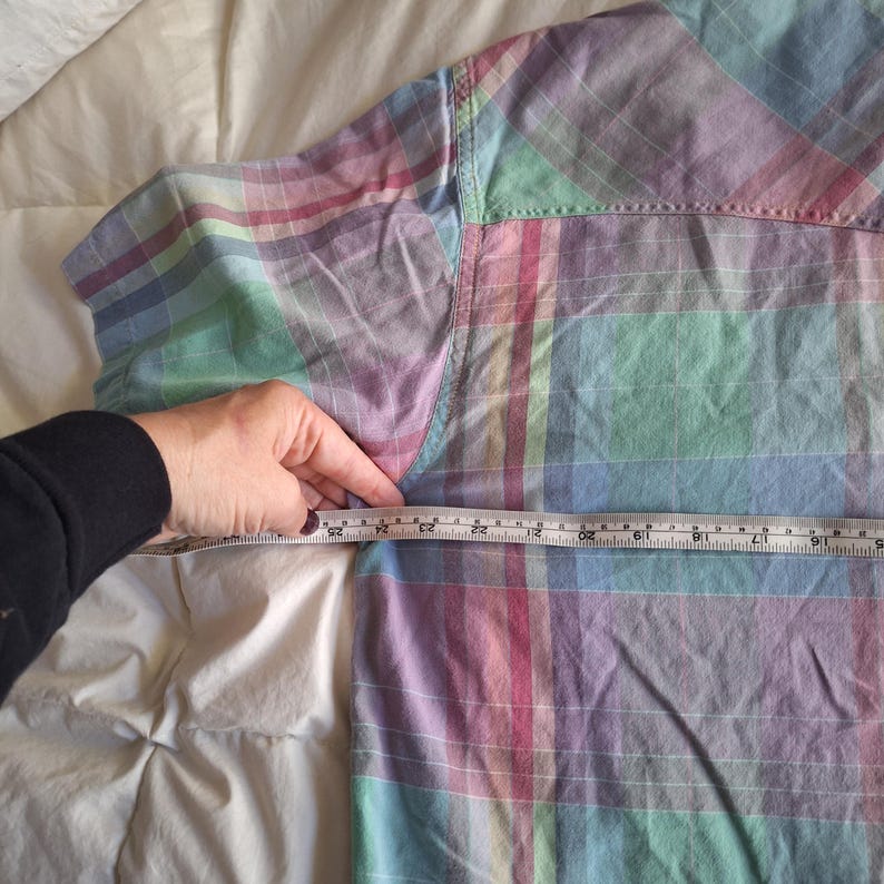 K&ouml;nnte beinhalten: Ein pastellfarbenes kariertes Button-Down-Hemd in Rosa-, Blau-, Gr&uuml;n- und Lilat&ouml;nen. Das Hemd wird mit einem Ma&szlig;band gemessen. Die Ma&szlig;e des Hemdes werden in Zentimetern gemessen.