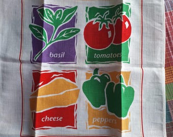 Könnte beinhalten: Weißes Küchentuch mit rotem Rand. Es zeigt vier Quadrate mit Illustrationen und Text: Basilikum, Tomaten, Käse und Paprika. Der Text ist in einer einfachen, klaren Schriftart gehalten.