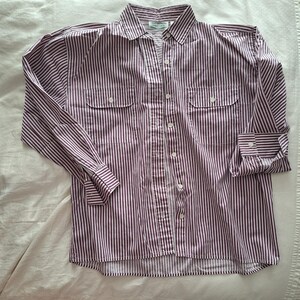 May include: A long-sleeved button-down shirt featuring a vertical striped pattern in dark maroon and white. The shirt includes a standard collar, a central button placket, and two chest pockets with buttoned flaps. The cuffs also feature buttons.