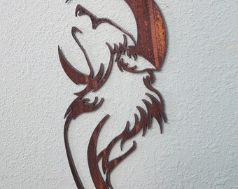 Op de afbeelding: Een rustiek metalen wandkunstwerk dat het silhouet van een huilende wolf tegen een halve maan afbeeldt. Het kunstwerk heeft een gedetailleerd uitgesneden ontwerp met een verweerde, bruine afwerking. De kop en het lichaam van de wolf zijn zichtbaar, wat een opvallende decoratie met natuuurthema creëert.