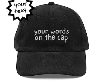 May include: A black corduroy baseball cap featuring the embroidered phrase "your words on the cap" in white. A starburst graphic with the words "your text" is in the upper left corner. The cap has a curved peak and a button on top.