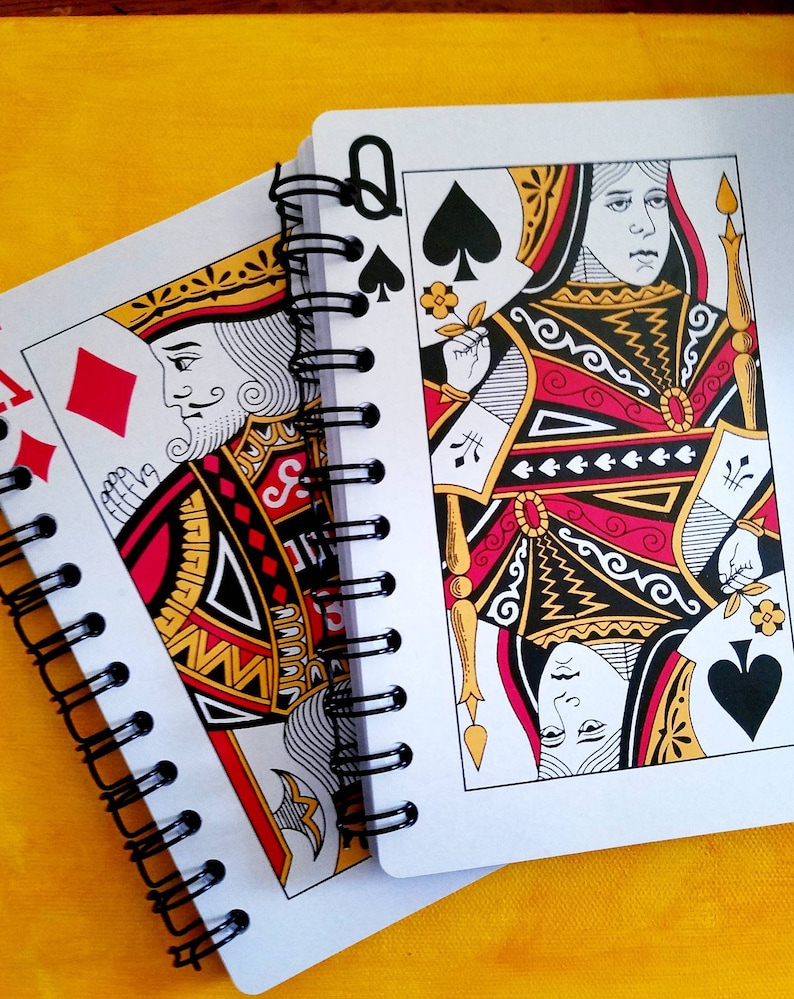 A 5 x 7 notebook with covers made from oversized playing cards. Traditional red black and gold face card motif. Black spiral binding with 60 blank pages of 80-pound paper. Clear lid box with stretch cord, gift tag and coordinating red pen. Great gift