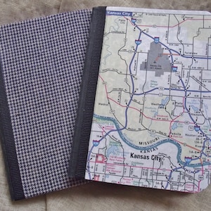 May include: A black and white checkered notebook cover with a black border. The cover is attached to a map of Kansas City, Missouri. The map shows major roads, highways, and points of interest. The map is titled "Kansas City" and includes the text "Missouri" and "Kansas".