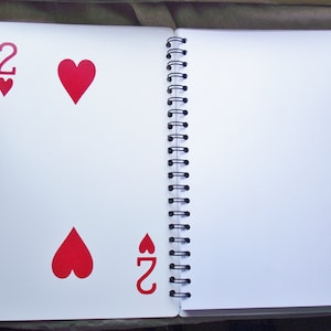 The center of the notebook features a playing card for stability.