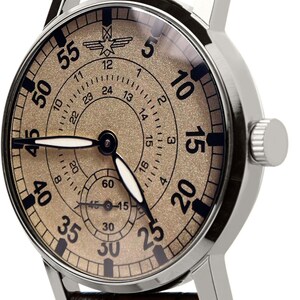 May include: A silver-cased wristwatch with a textured tan face and black numerals. The watch features a black leather band and a small seconds dial. The watch hands are black and white.