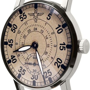 May include: Silver-toned wristwatch with a mesh band. The watch face is tan with black numerals and hands. The watch has a small seconds dial and a 24-hour clock. The band is made of a fine, woven metal.