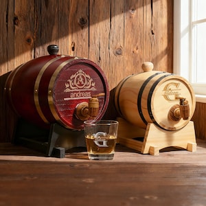 May include: Two wooden barrel-shaped liquor dispensers. One is stained red with gold accents and the name "andreas". The other is natural wood with black bands and the name "Gideon". Both have spouts and sit on wooden stands. A glass with the letter "G" is in front.