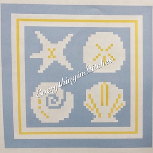 May include: A blue and yellow cross-stitch pattern featuring a starfish, a seashell, a sand dollar, and a seashell with a yellow design. The pattern is titled "Everything in Stitches".
