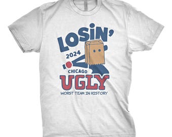 May include: White t-shirt with blue and red text that says "Losin' 2024 Chicago Ugly Worst Team in History". A cartoon figure with a paper bag over its head is holding a baseball bat.