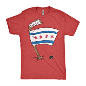 Op de afbeelding: Rood T-shirt met een afbeelding van een hockeystick en de vlag van Chicago.