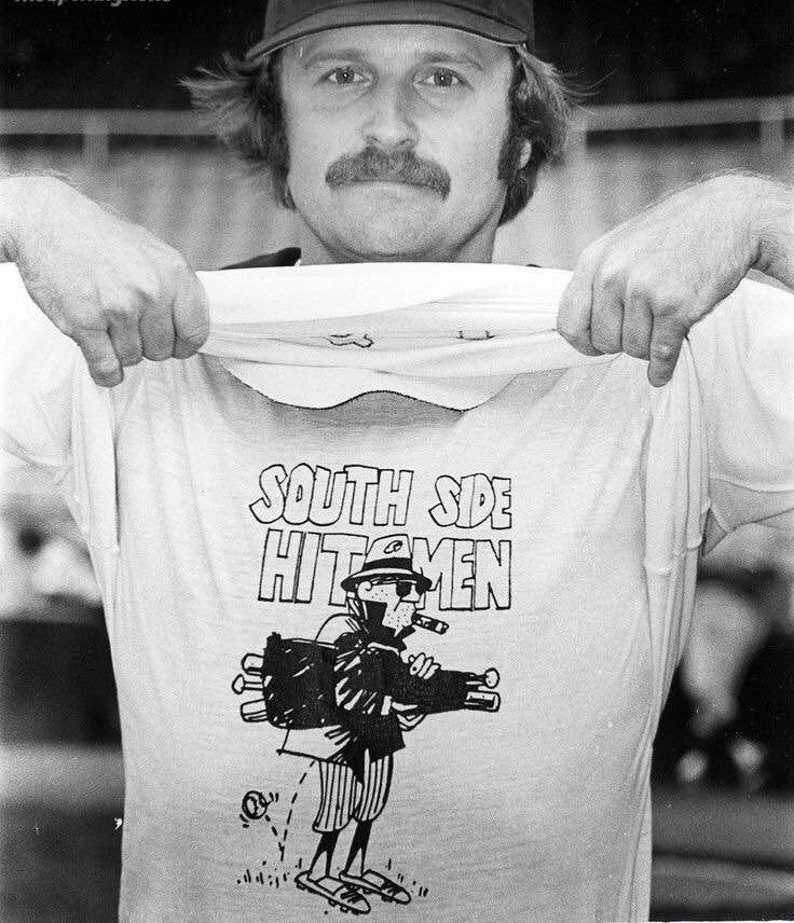 Puede incluir: Una fotograf&iacute;a en blanco y negro de una persona que lleva una gorra de b&eacute;isbol y una camiseta blanca con el texto "South Side Hitmen" y una ilustraci&oacute;n de dibujos animados de una persona que sostiene una bolsa de bates.