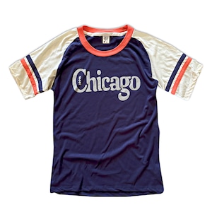 May include: A navy blue t-shirt with a white and red baseball-style striped sleeve. The shirt has a white "Chicago" graphic with a football graphic above the text.