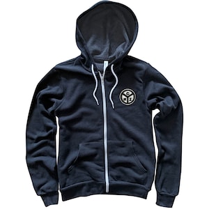 Può includere: Una felpa con cappuccio nera con cerniera bianca e un logo bianco e nero sul petto sinistro. Il logo è un cerchio con le lettere "CNI" all'interno.