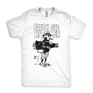 Puede incluir: Camiseta blanca con una ilustraci&oacute;n en blanco y negro de un hombre con sombrero y gafas de sol, sosteniendo una bolsa de golf y un cigarro. El texto "SOUTH SIDE HITMEN" est&aacute; impreso sobre la ilustraci&oacute;n.