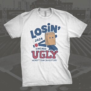 May include: White t-shirt with a blue and red graphic of a paper bag with a face and the text "Losin' 2024 Chicago Ugly Worst Team in History".