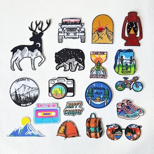 Può includere: Una collezione di toppe ricamate a tema outdoor che include un cervo, una jeep, montagne, una lanterna, un orso, una clessidra con testo, uno zaino, una fotocamera, una bicicletta, una cassetta, una tenda, scarponi da trekking e occhiali.